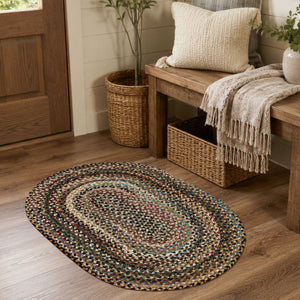 Multicolor oval braided jute rug in a cozy farmhouse entryway with a rustic wood bench, woven baskets, neutral pillows, and warm wood flooring.