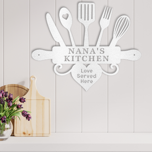Decorative metal wall art with kitchen utensils and 'Nana's Kitchen' text on a light wooden background.
