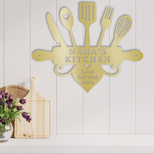 Decorative metal wall art with kitchen utensils and 'Nana's Kitchen' text on a white wooden panel.