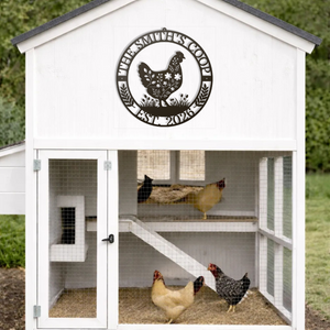 White chicken coop with a circular sign featuring a rooster design, and three chickens inside.