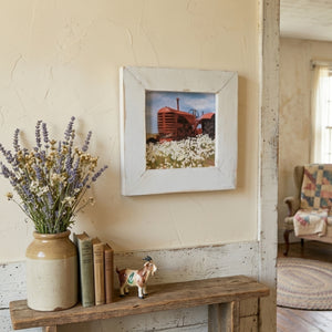 Nostalgic interior with a wooden bench, framed picture of a tractor, and decorative items.