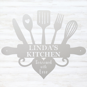 A white personalized kitchen wall sign featuring silhouettes of kitchen utensils and a rolling pin with the text 'LINDA'S KITCHEN' and 'Seasoned with Love' in white on a light gray background.