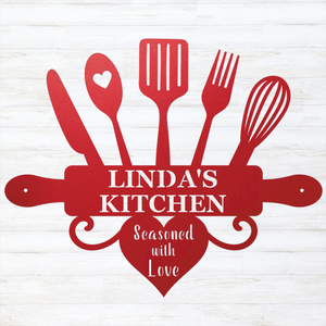 A red kitchen-themed decorative sign or cutout featuring utensil silhouettes, a rolling pin, a heart, and the text 'LINDA'S KITCHEN' with 'Seasoned with Love' below, shown on a white wood-plank background.