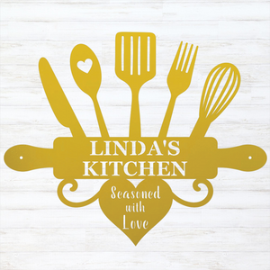 A yellow kitchen-themed decorative sign or silhouette design featuring a knife, spoon with a heart, spatula, fork, whisk, rolling pin, and heart shape with the text 'LINDA'S KITCHEN' and 'Seasoned with Love,' shown on a white wood-plank background.