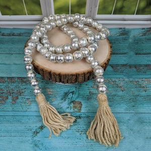 Beaded necklace with tassels on a wooden slice against a blue wooden background