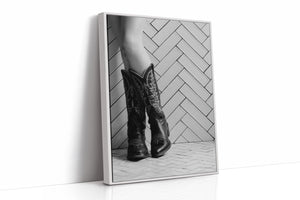 Framed black and white photo of cowboy boots on a wooden floor.