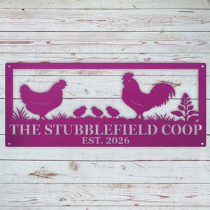A rectangular metal sign with a magenta purple background and silhouette cutouts of a rooster, hen, two chicks, and plants. The sign reads 'THE STUBBLEFIELD COOP EST.