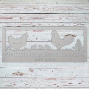 A rectangular metal sign with a distressed gray finish, featuring silhouettes of a rooster, hen, chicks, and plants, with the text 'THE STUBBLEFIELD COOP EST. 2026' cut out.