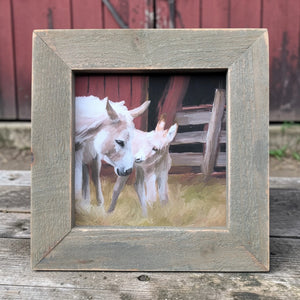 Two donkeys in a wooden frame with a rustic background