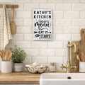  Custom Kitchen sign on a tiled wall above a kitchen counter with utensils and plants.