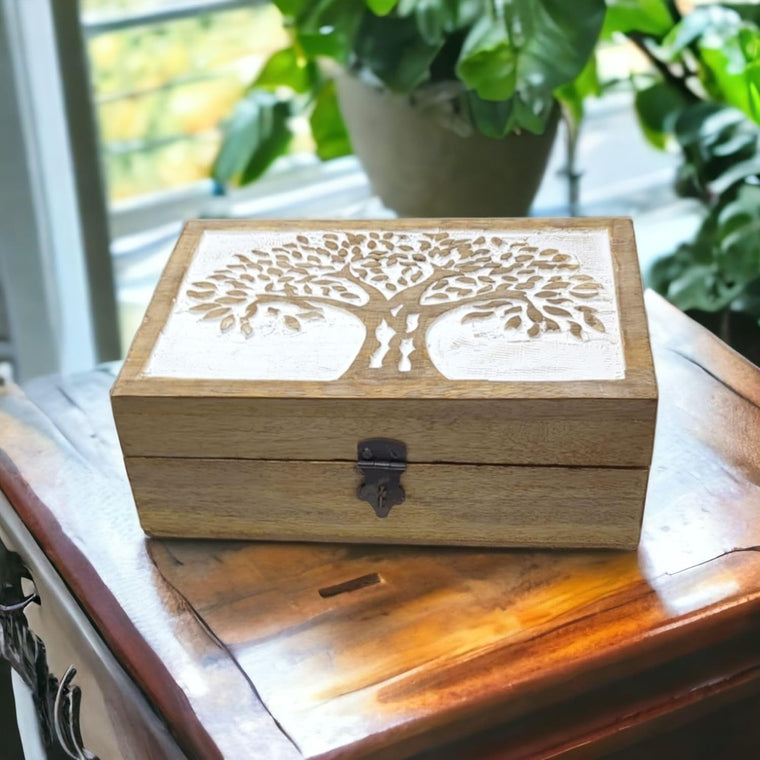 Wooden box with tree design on a wooden surface with plants in the background