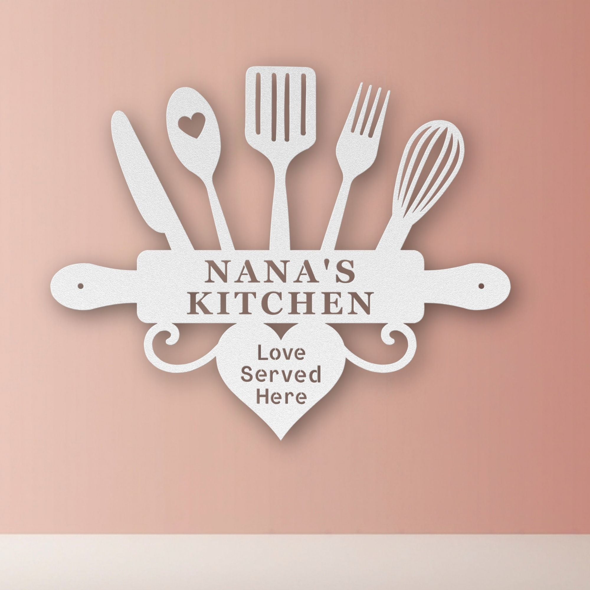 Decorative sign with kitchen utensils and 'Nana's Kitchen Love Served Here' text on a pink background