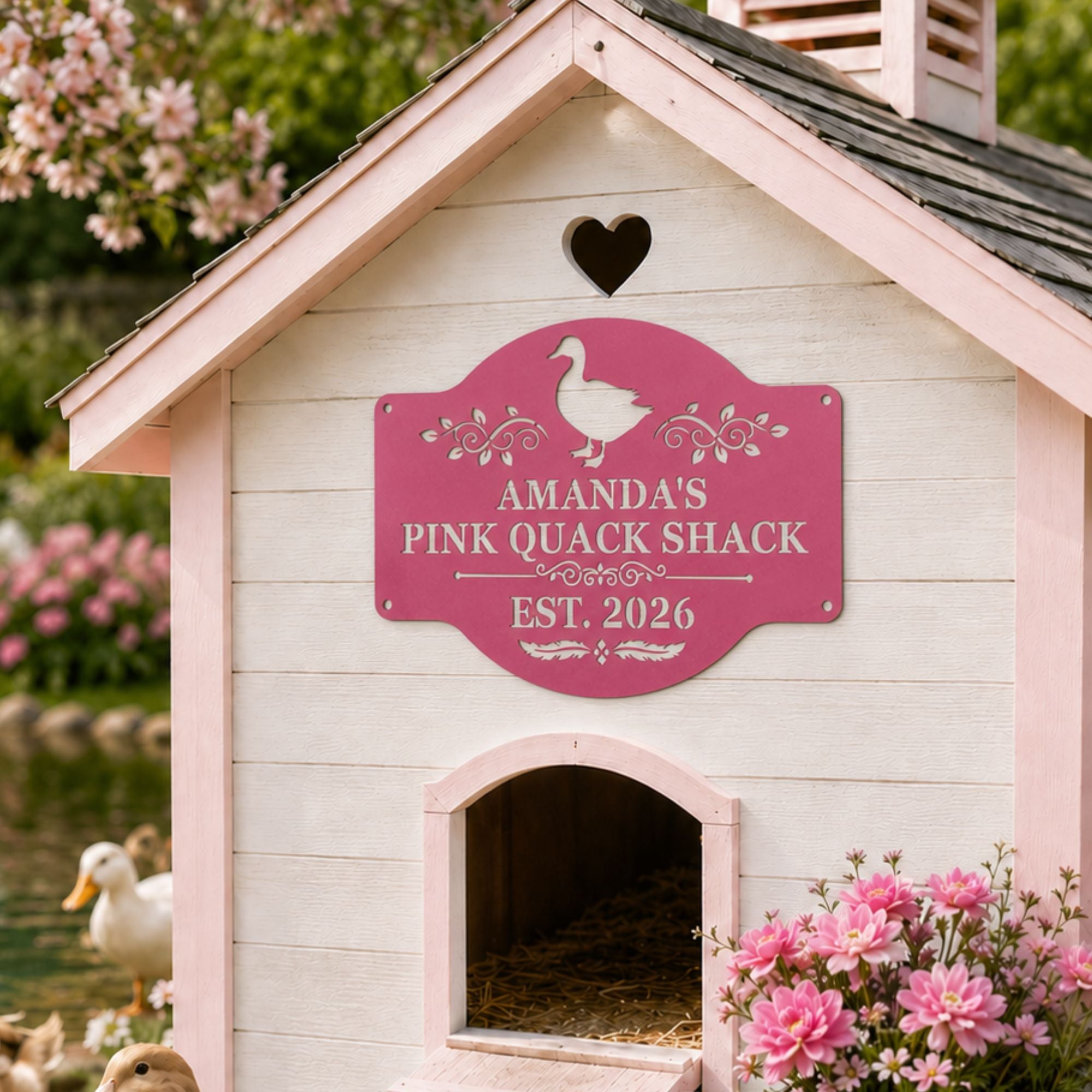 Pink personalized duck house sign mounted on a white and pale pink duck house with white and tan ducks, pink flowers, and a pond in a spring garden setting.