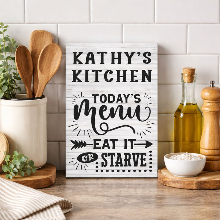 Decorative sign in a kitchen with personalized name and text 'Today's Menu Eat It or Starve' on a white background.