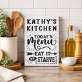 Decorative sign in a kitchen with personalized name and text 'Today's Menu Eat It or Starve' on a white background.