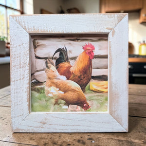 Framed picture of two chickens on a wooden surface