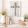 Decorative wall sign with 'AM GRAC ZING' text, books, flowers, and a candle on a wooden surface.