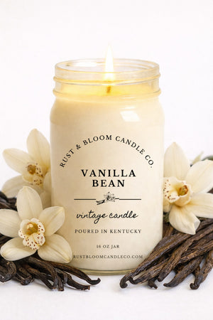 Farmhouse World Vanilla Bean Vintage Candle in a 16 oz jar, surrounded by vanilla beans and orchids. Creamy vanilla scent.