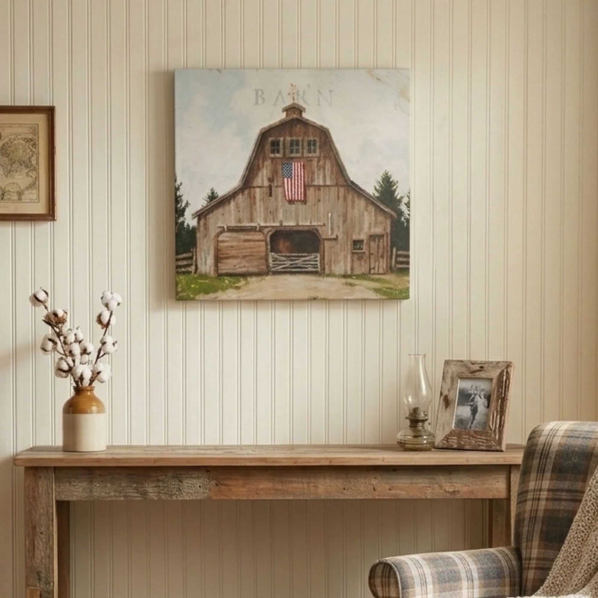 Wooden barn painting on a wall above a wooden console table with decorative items.