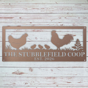 A rectangular metal sign with a rustic wood-plank background design, featuring silhouettes of a rooster, hen, three chicks, and plants. The sign is personalized with the text 'THE STUBBLEFIELD COOP' and 'EST.