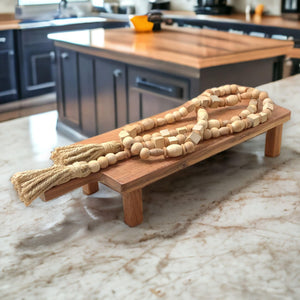 Farmhouse World boho wood bead garland with tassels on a tray