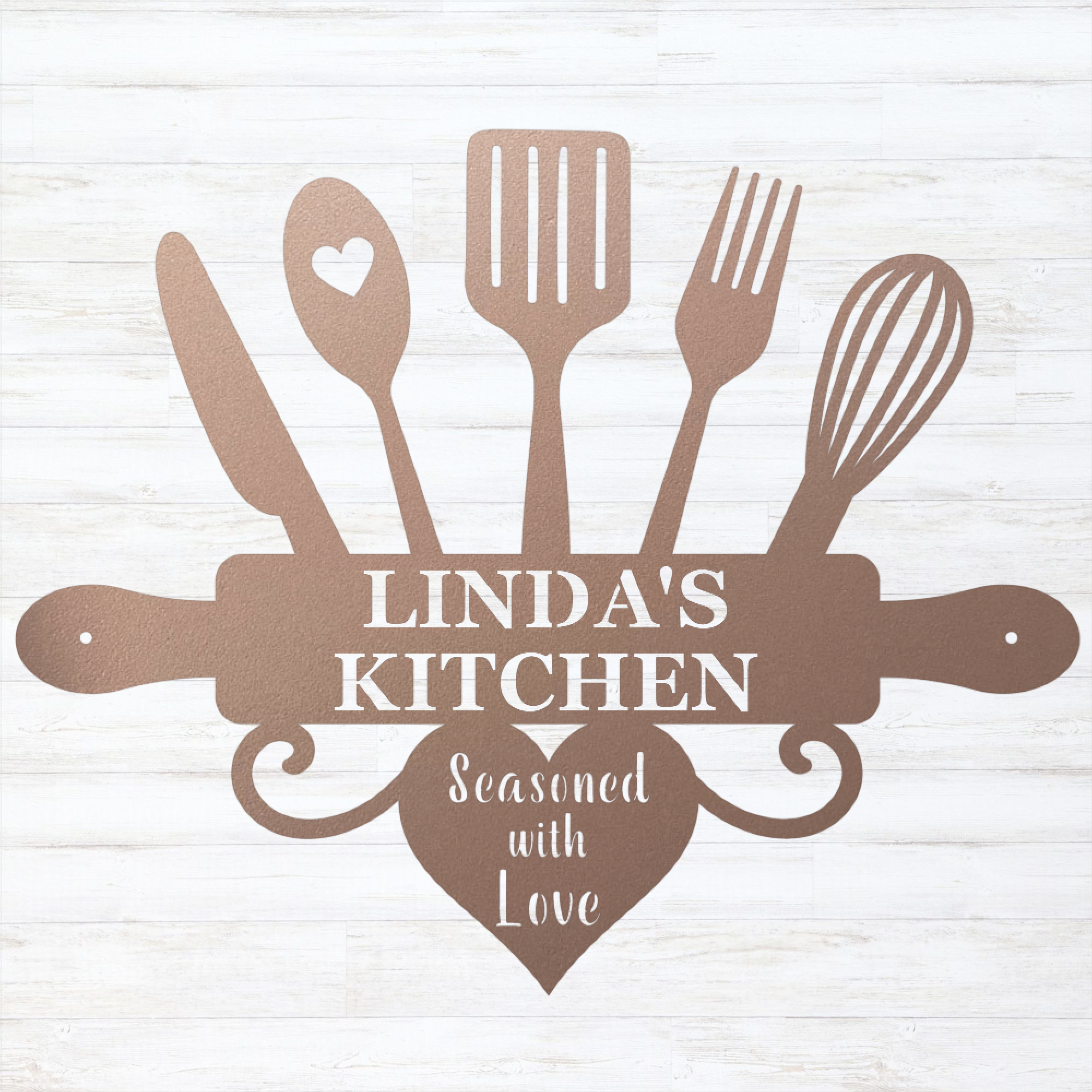 A decorative kitchen-themed sign or plaque with silhouettes of cooking utensils and a rolling pin, reading “LINDA'S KITCHEN” and “Seasoned with Love,” shown on a light whitewashed wood background.